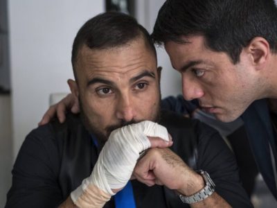 Uomo con mano fasciata viene consolato da un altro uomo.